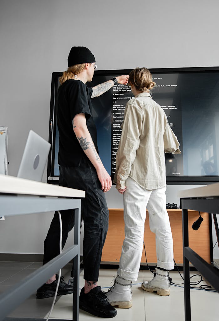 Two young adults collaborating on a coding project in a modern office setting.